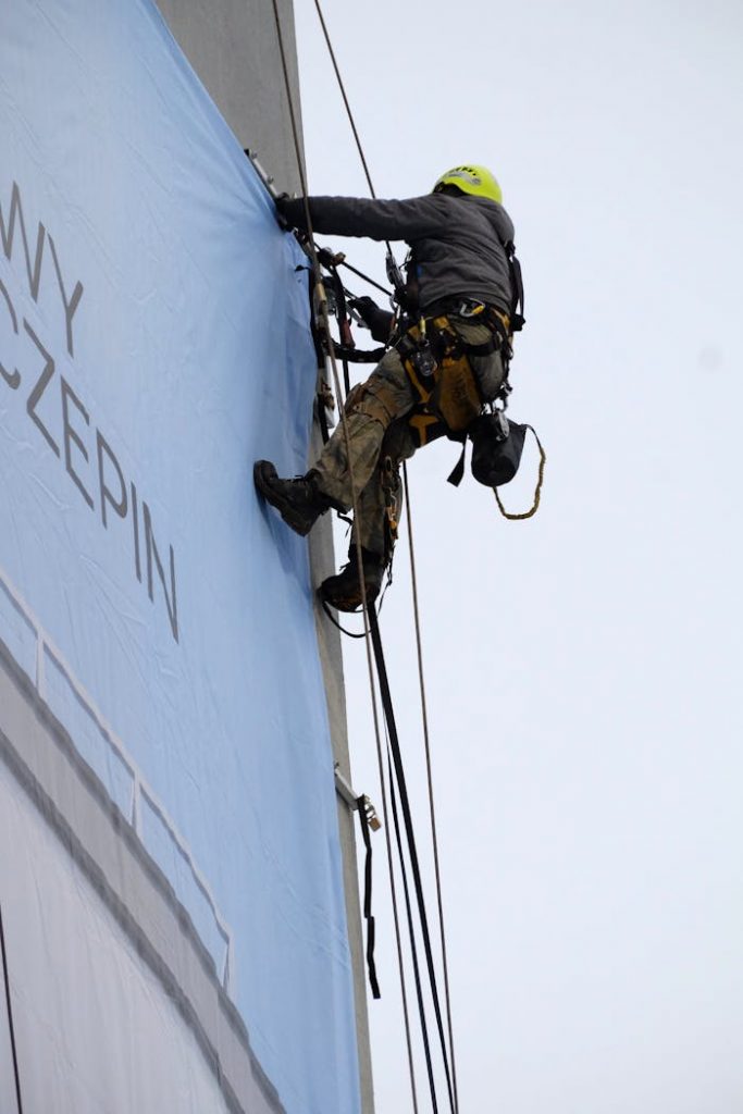 Professional rope access technician working on a building facade, using safety gear.