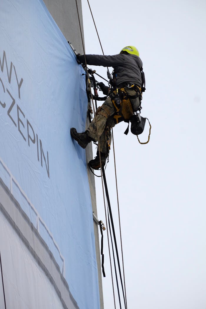 Professional rope access technician working on a building facade, using safety gear.